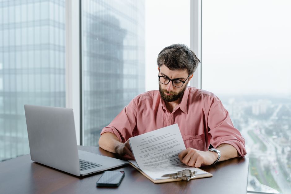 Professional man in pink shirt working with documents at a modern office desk.